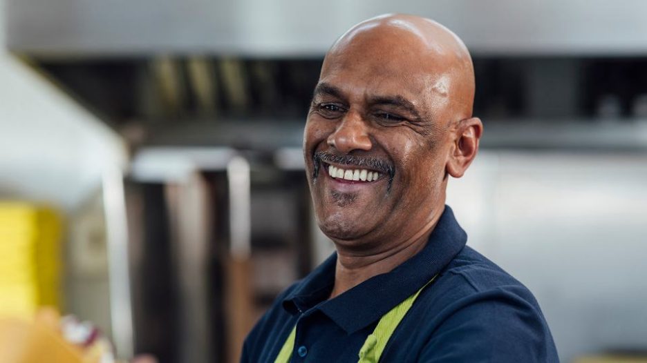 African middle-aged man smiling while working at his job