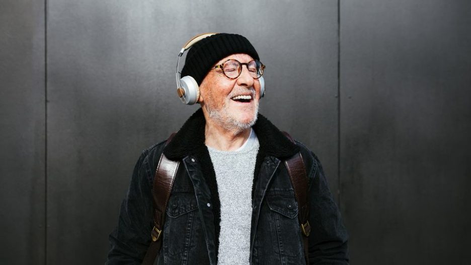 senior man with headphone smiling outdoors