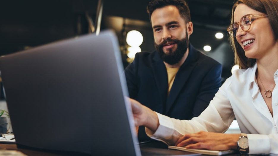 man and woman looking at laptop together and smiling