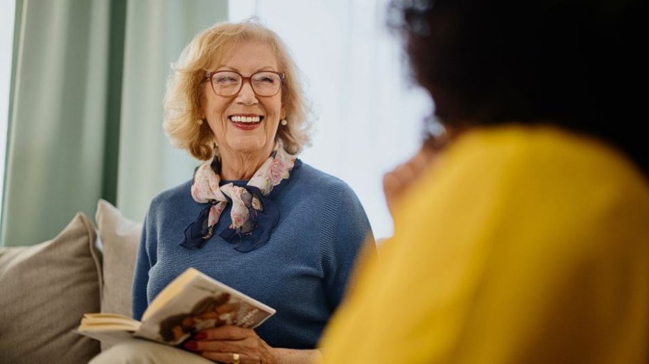 seniorwoman with glasses at a book club smiles at another woman
