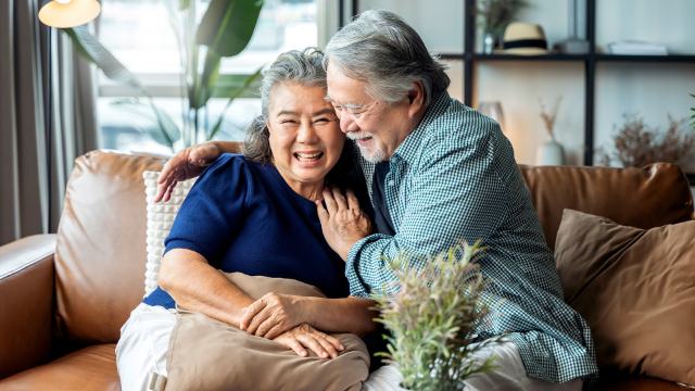 mature couple cuddling on a brown leather sofa at home