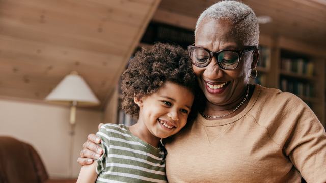 smiling grandmother enjoying a hug from a boy in a striped tee shirt