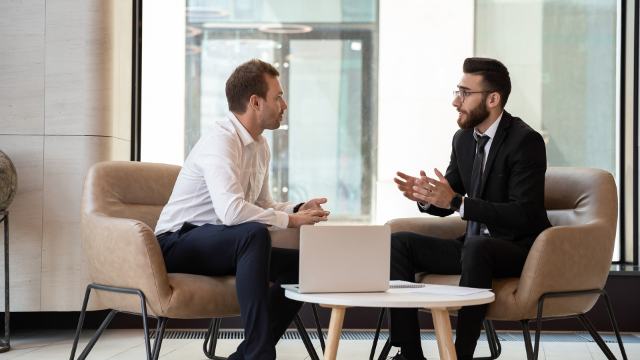 male-professional-meeting-office-laptop.jpg two men having an informal meeting in comfortable office chairs in a modern setting