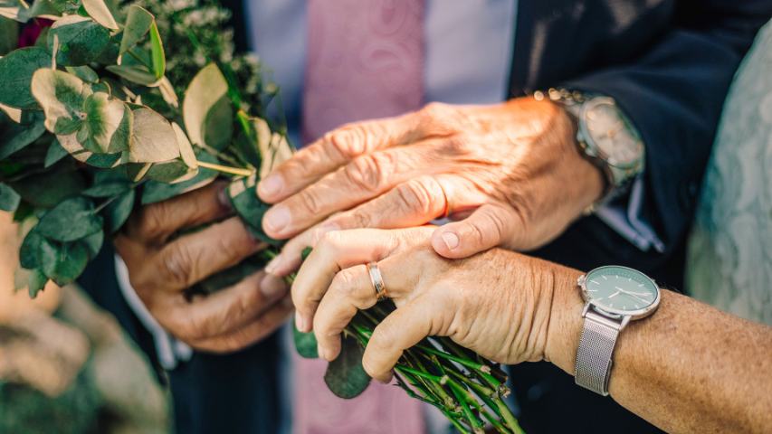 elderly couple holding flowers while holding hands