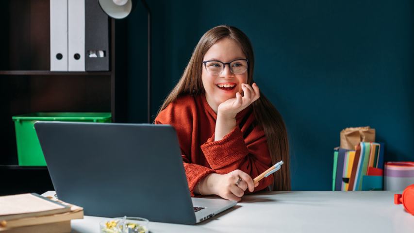 girl with down syndrome using laptop at home