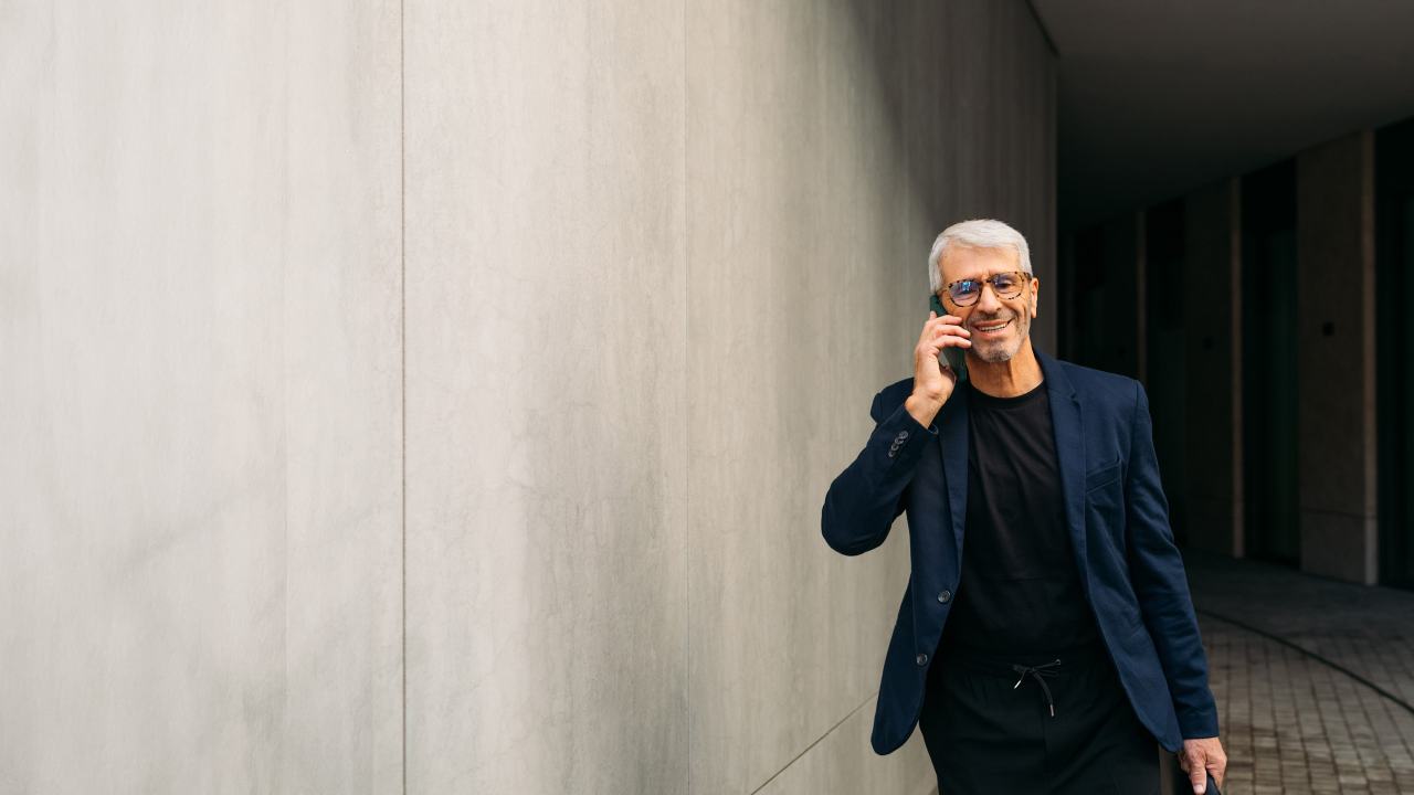 smartly dressed senior man talking on his smartphone outside