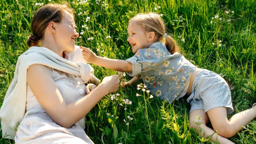 mum and young girl lying on grass playing