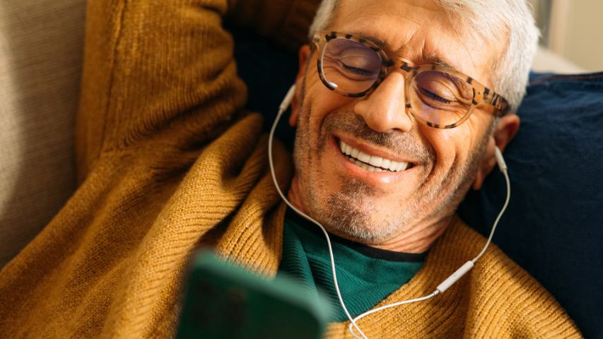 senior man laying on couch using his mobile phone 