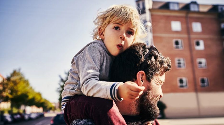 man looking away from camera with young boy on his shoulders