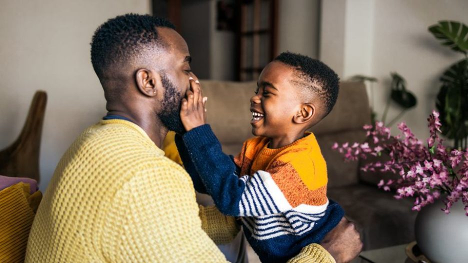 side view of a father having fun with his son in the living room at home