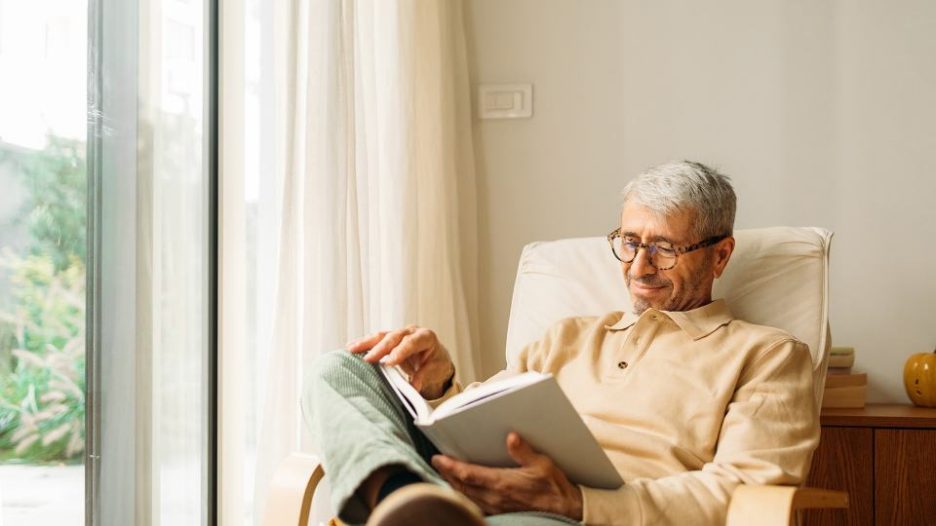 relaxed senior man sitting in armchair and reading book