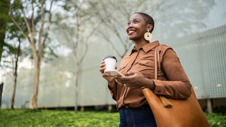 woman outside smiling with coffee cup