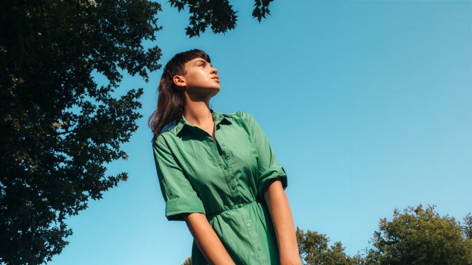 young woman wearing a green dress with the blue sky behind