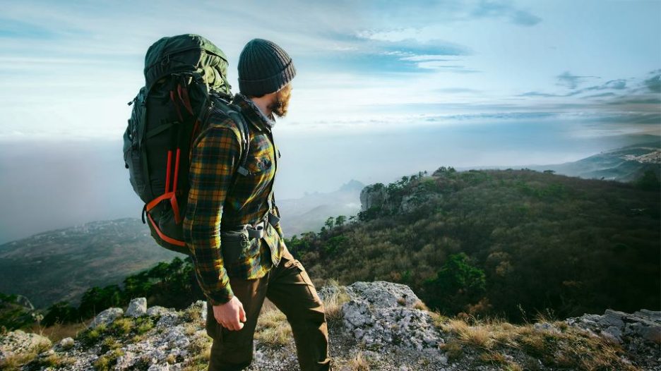 man traveling with backpack hiking in mountains