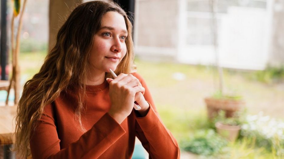 woman sitting in a cafe looking thoughtful