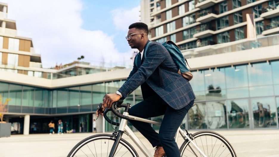 young man wearing a suit and backpack cycling in the city