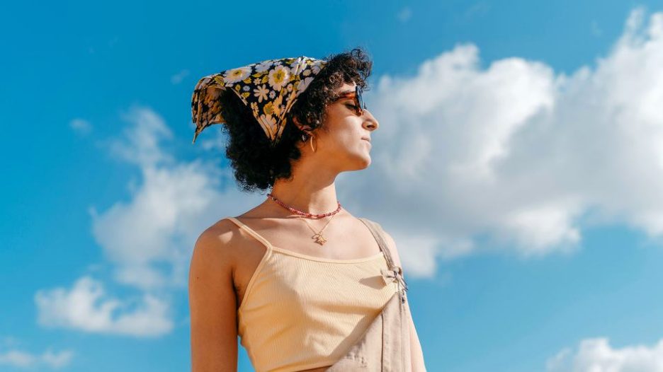 young woman wearing sunglasses looking up to the sunny sky