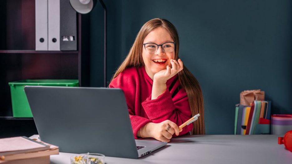 young girl sitting at desk using laptop