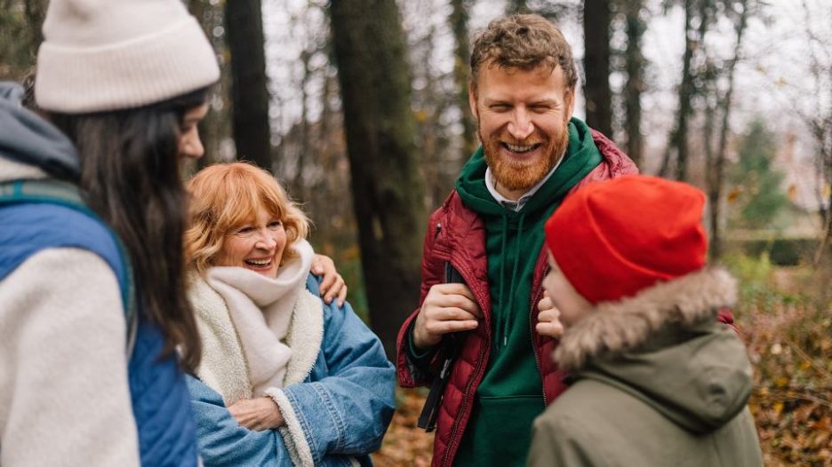 family of hikers in winter clothes standing and laughing in nature