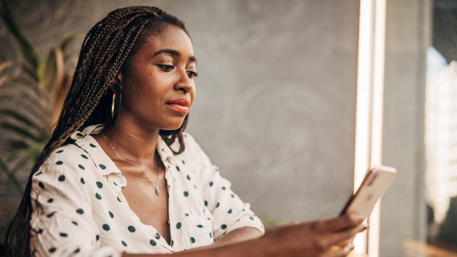 woman in a polkadot shirt using her phone while seated inisde